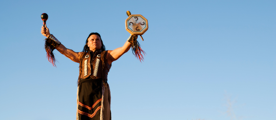 Native American religious leader performing ceremony against blue sky