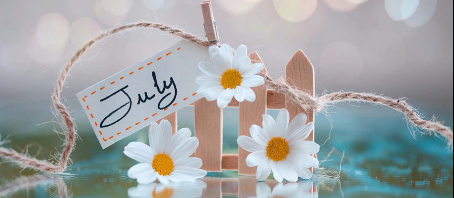 Little wooden fence with daisies, twine, clothespin, and July tag on it