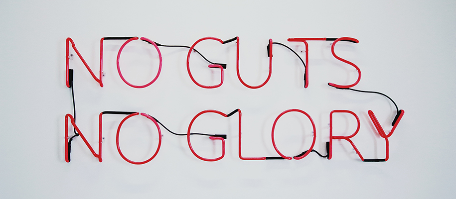 Red neon connected-letter sign reading no guts not flory on white background