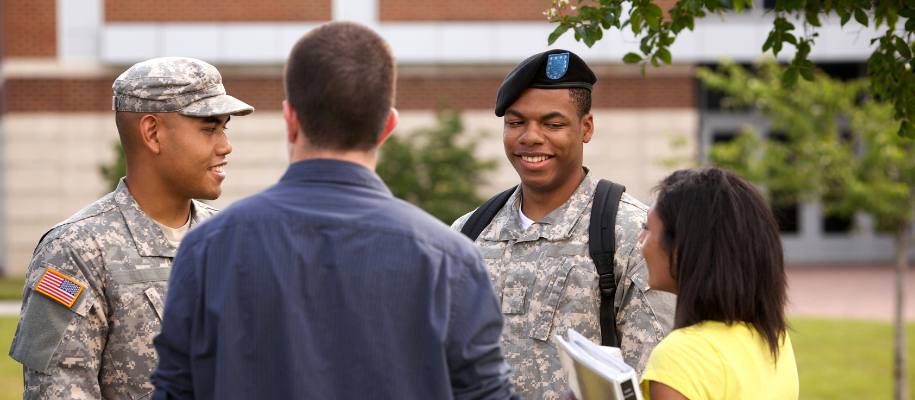 Two ROTC army students in uniform talking with two civilian students on campus