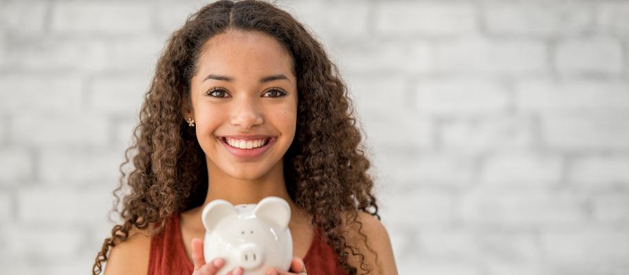 Young Black woman with long curly hair, smiling with white piggy bank