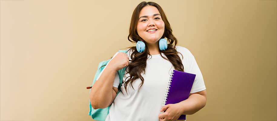 Smiling young plus-sized Hispanic woman with backpack, notebook, headphones