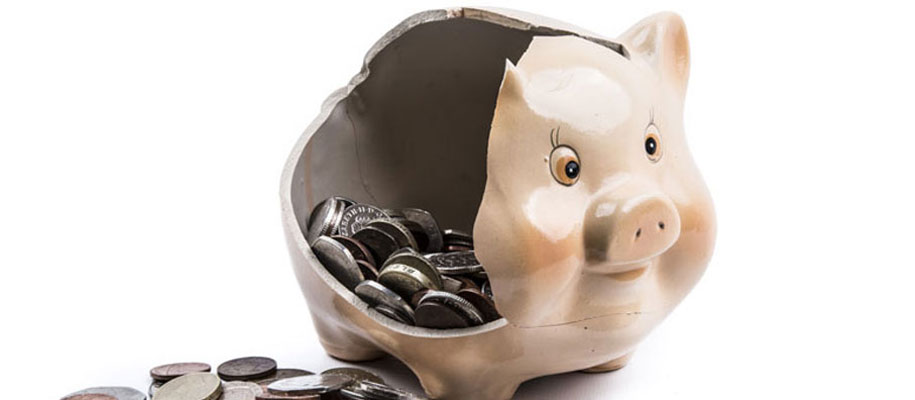 Pale pink piggy bank with one side smashed in to reveal coins