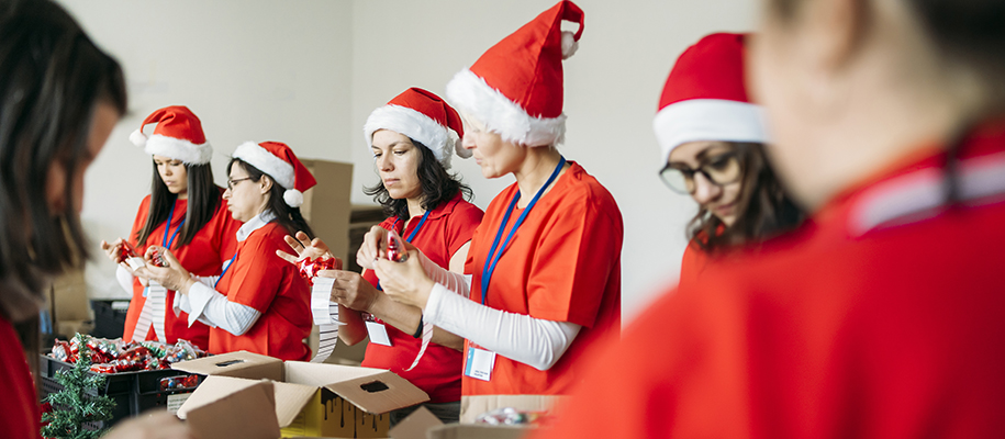Group of people in Santa hats and red shirts sorting donations