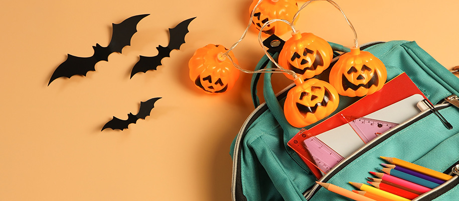 Backpack of school supplies with jack-o’-lantern lights and paper bats