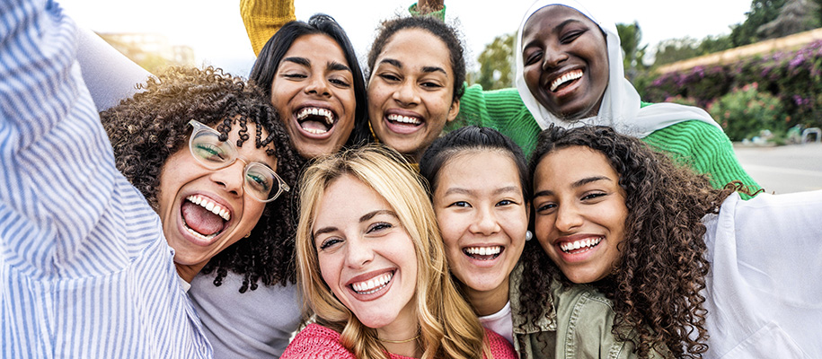 Group of seven diverse women smiling and laughing together outside