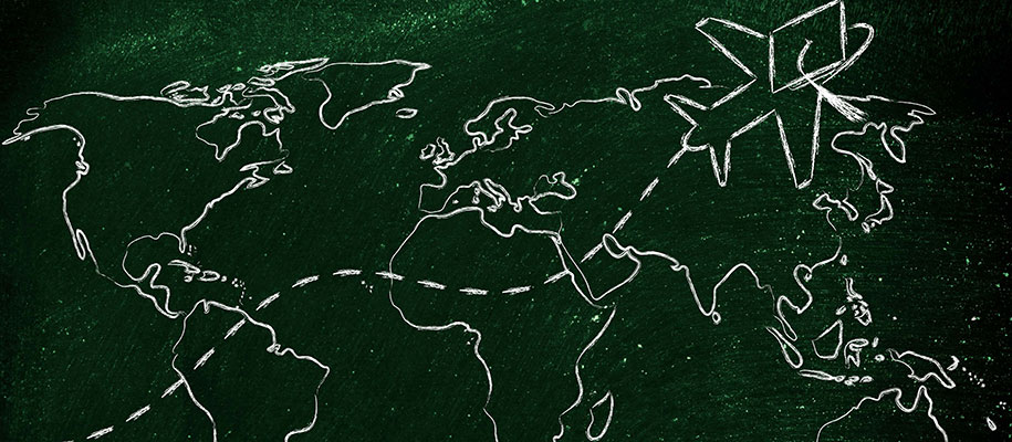 Chalkboard drawing of airplane wearing graduation cap flying across world map