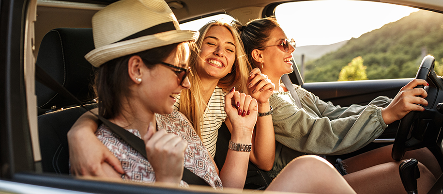 Three young White women driving in a car, smiling and laughing