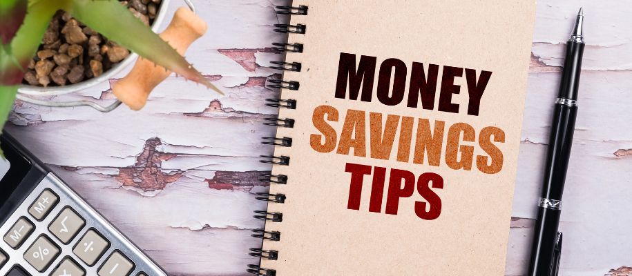 Birch table with calculator, pen, plant, and notebook with Money Savings Tips on