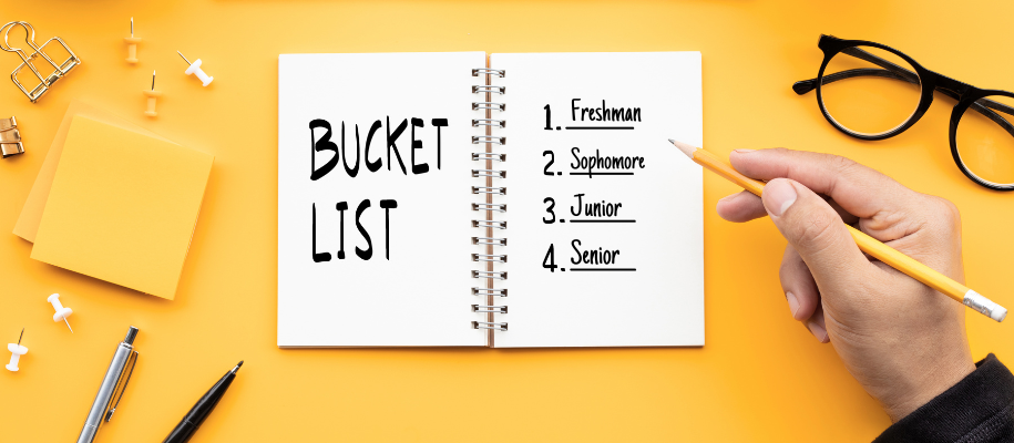 Hand holding yellow pencil over high school bucket list on yellow backdrop