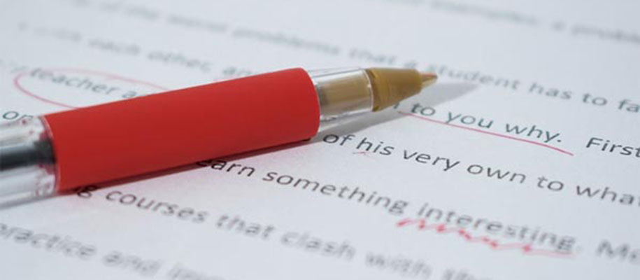 Red pen lying on typed essay with red editing marks