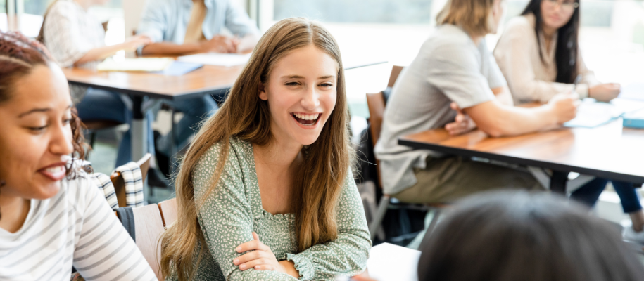 Young White woman in green blouse laughing in class of diverse students
