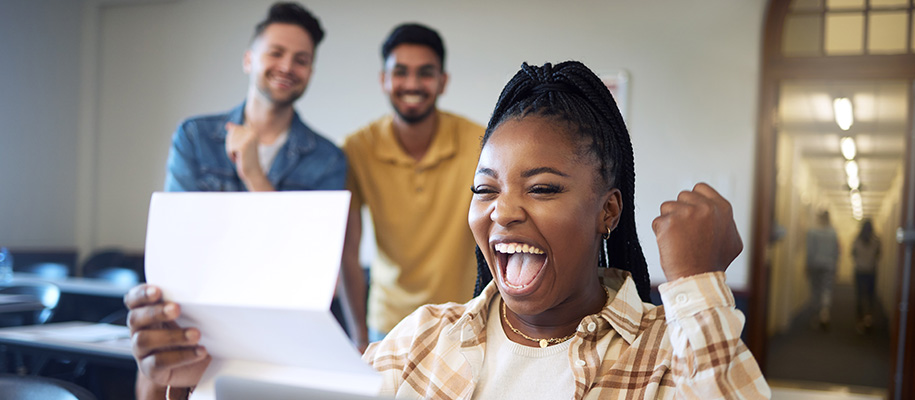 Excited Black woman in plaid holding letter, male friends excited behind her
