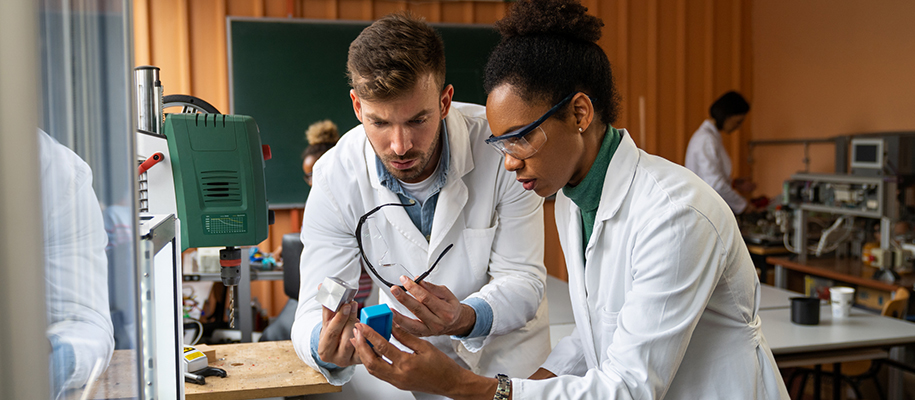 Black woman, White man in lab holding materials, work glasses, examining things