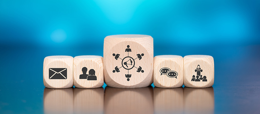 Five wooden cubes, largest in center, with icons of people communicating